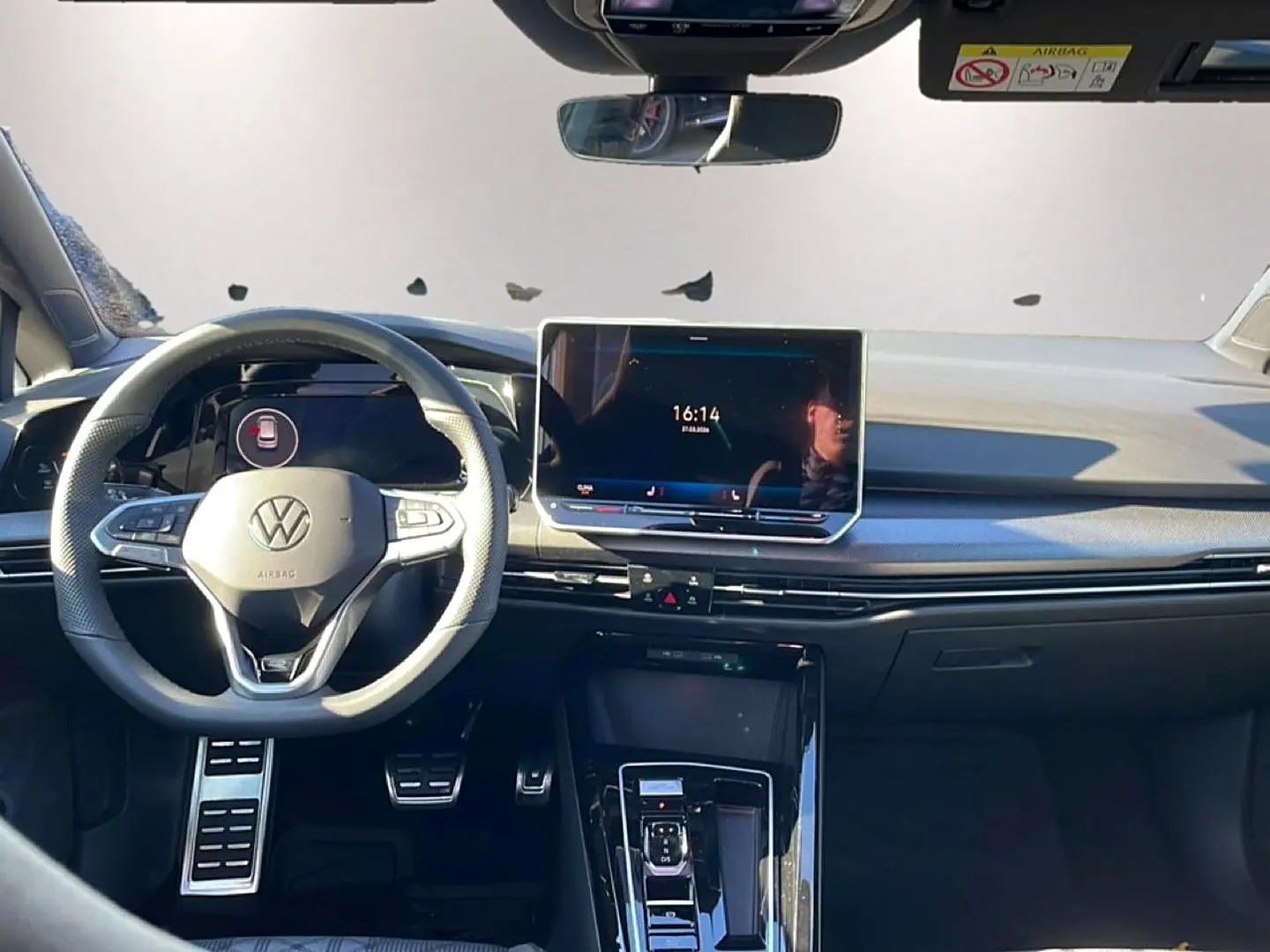 Vue frontale de l'intérieur noir de la Volkswagen Golf 1.5 etsi evo2 150 R-Line avec écran tactile central et volant multifonction.
