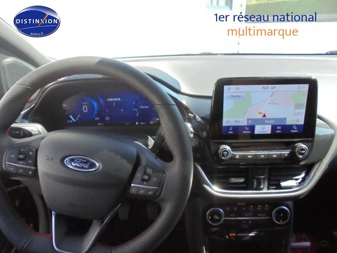 Vue intérieure du tableau de bord et volant noir perforé d'une Ford Puma 2022 avec écran tactile affichant la navigation GPS.