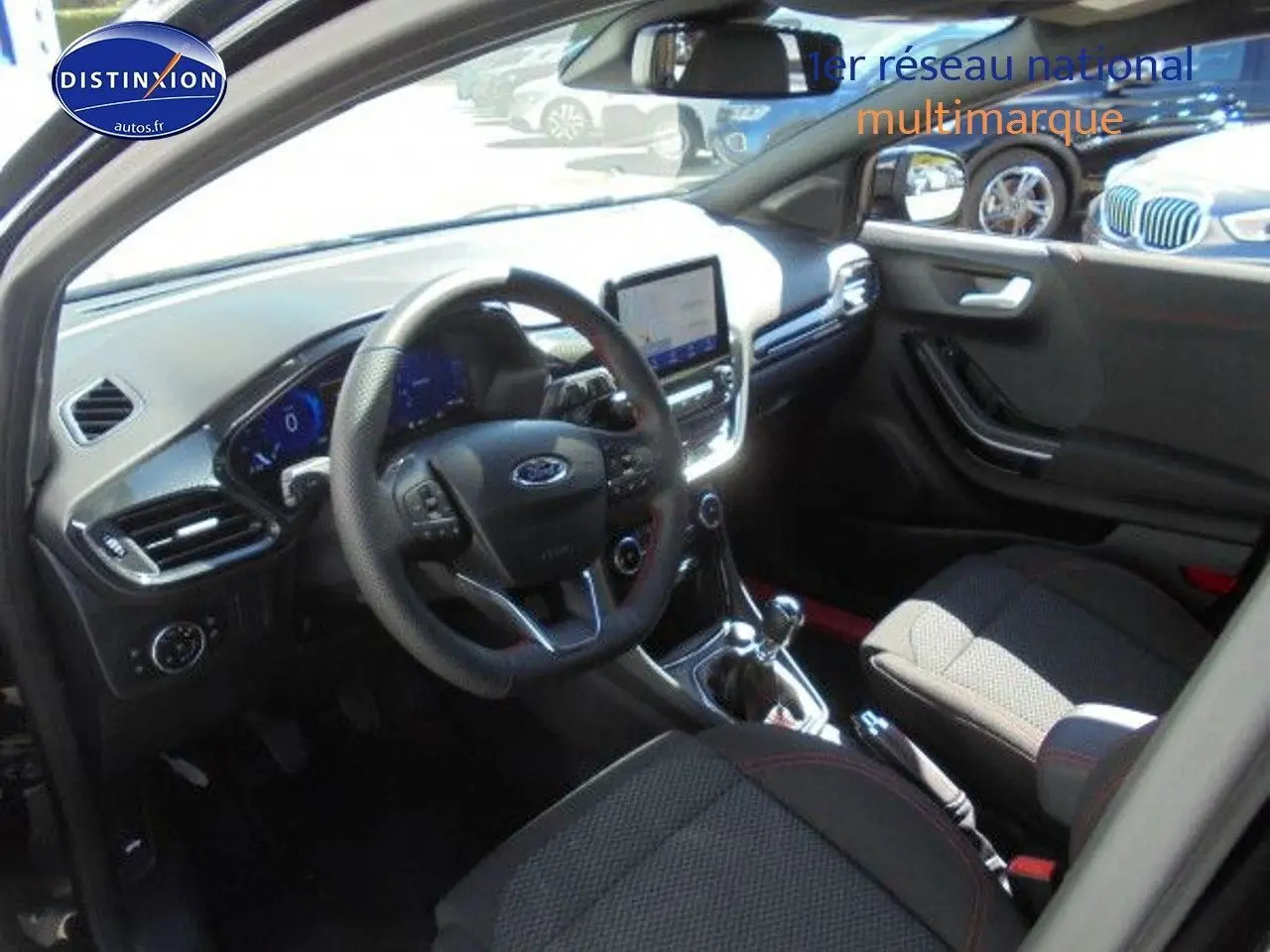 Vue intérieure côté conducteur du Ford Puma noir agate, mettant en valeur le tableau de bord et la boîte manuelle.