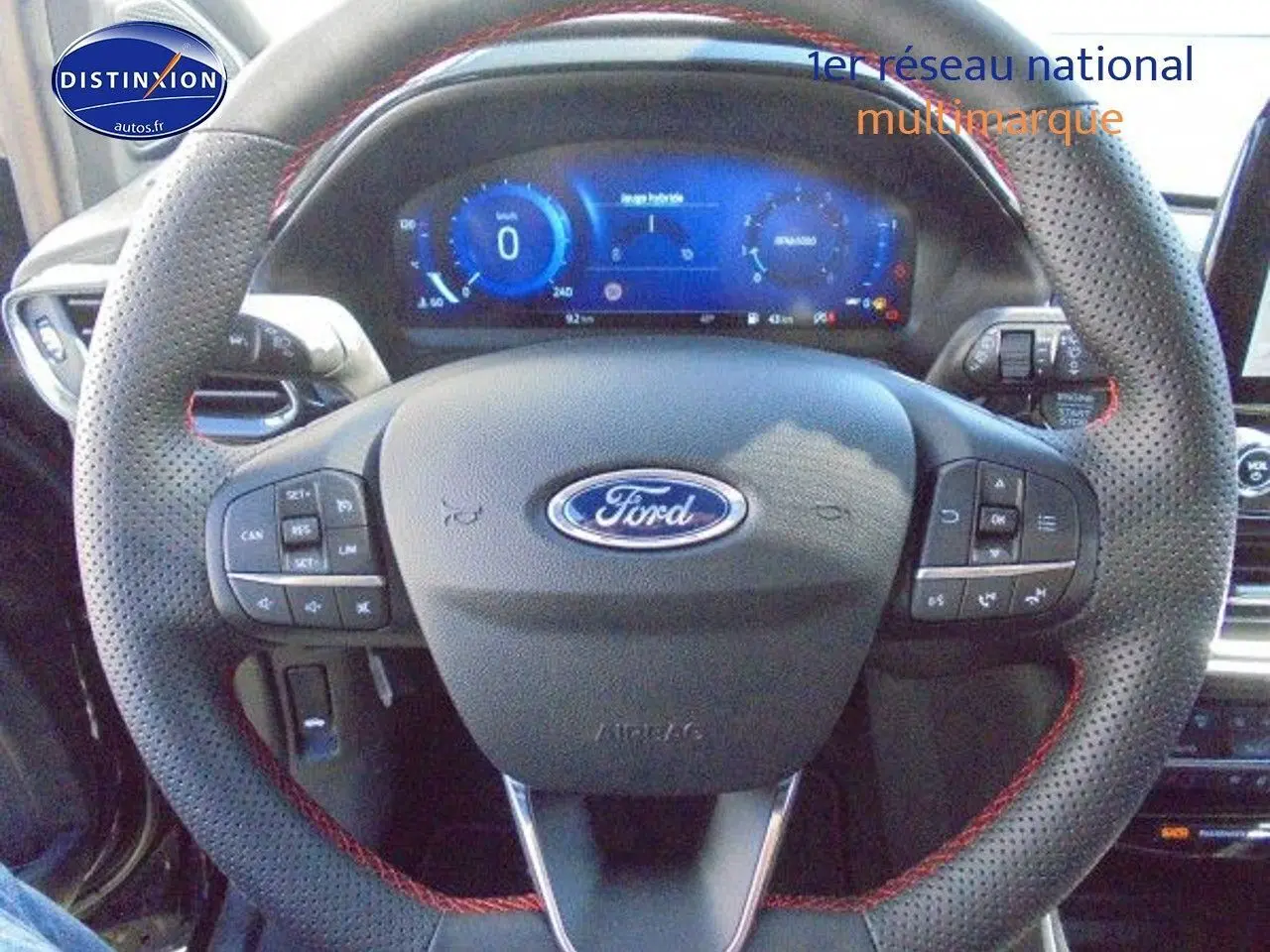 Volant perforé noir avec surpiqûres rouges et commandes intégrées, tableau de bord numérique de la Ford Puma 2022.