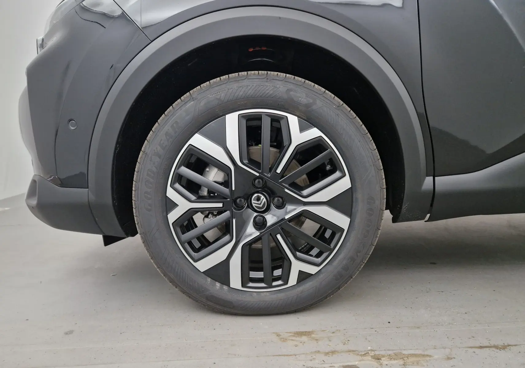 Gros plan sur la roue avant gauche noire d'une Citroën C4 1.2 HYBRID 136 e-DSC6 MAX avec jante alliage bicolore.