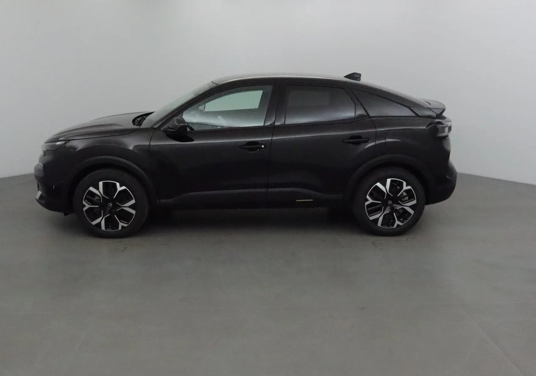 Profil latéral gauche d'une Citroën C4 noire 2025 avec jantes alliage et lignes épurées dans un studio neutre.