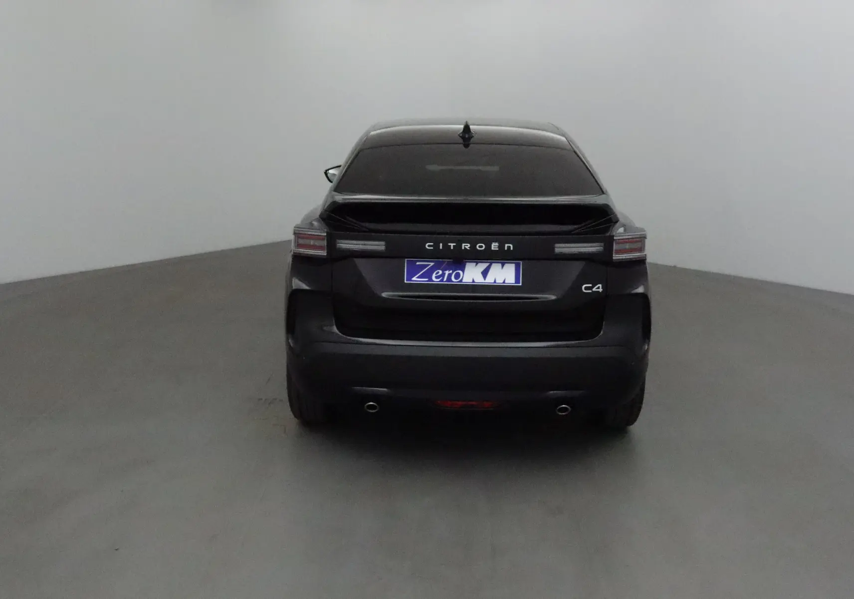 Vue arrière d'une Citroën C4 noire 2025 avec feux LED et double sortie d'échappement visible sur fond neutre.