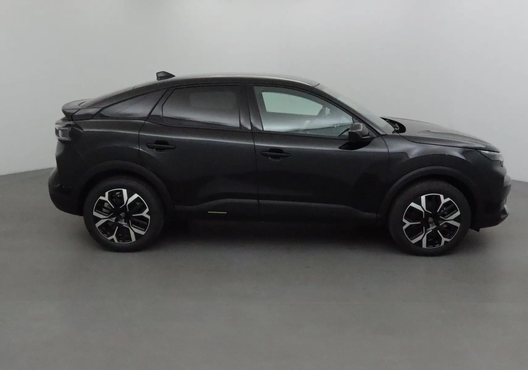 Profil côté gauche d'une Citroën C4 noire 2025 avec jantes alliage et lignes fluides modernes.