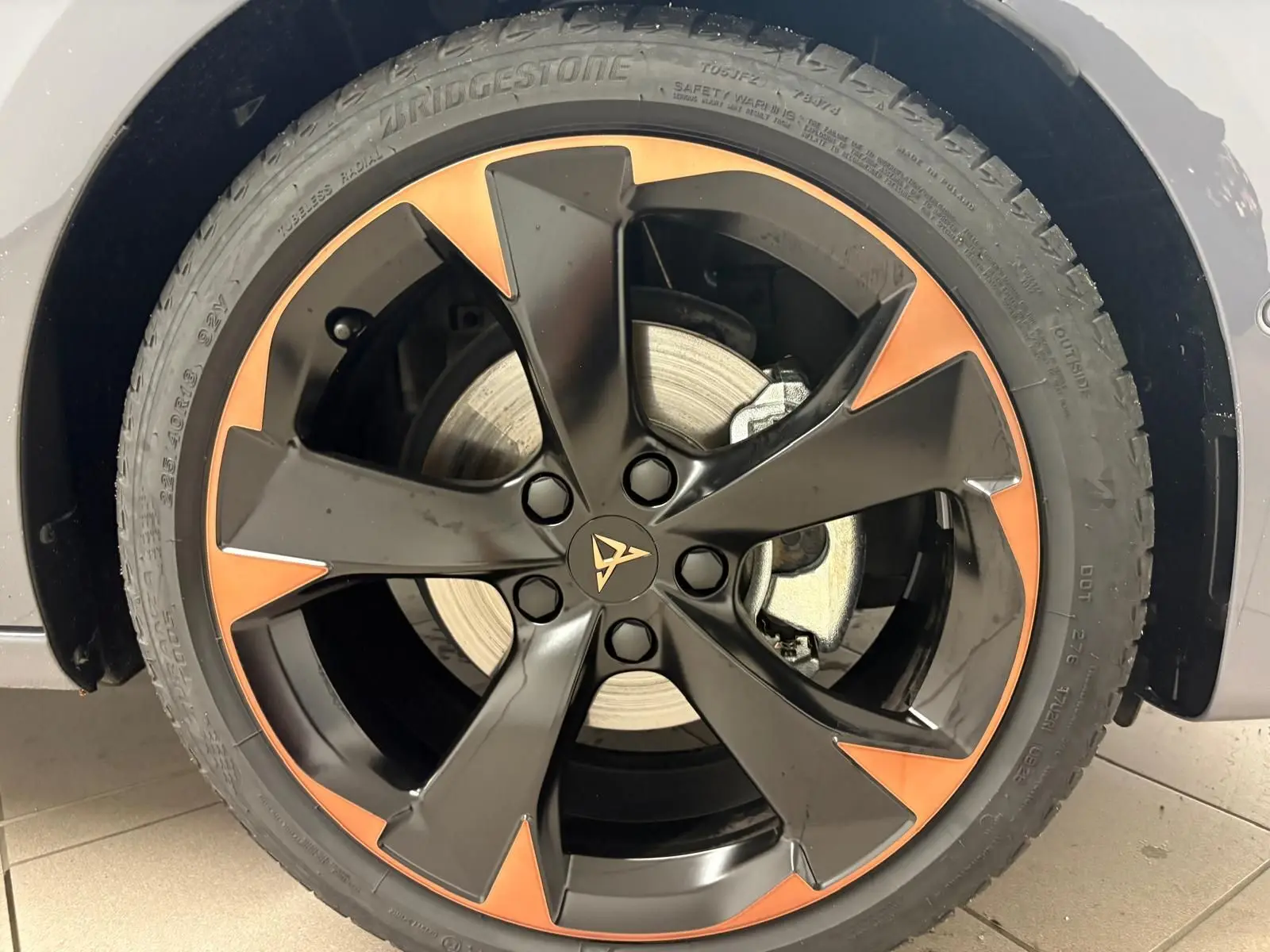 Gros plan sur la jante alliage 18'' cuivrée et noire du CUPRA Leon gris Graphène, mettant en valeur le logo central distinctif.