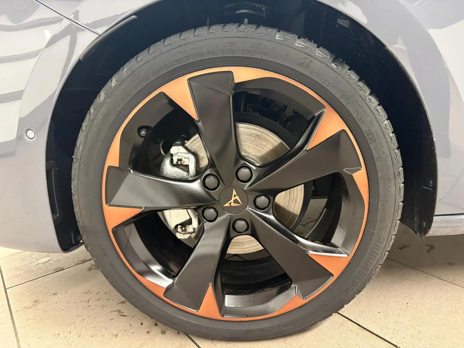 Gros plan sur la jante 18'' cuivrée et noire d'une CUPRA Leon Gris Graphène, avec frein visible derrière la roue.