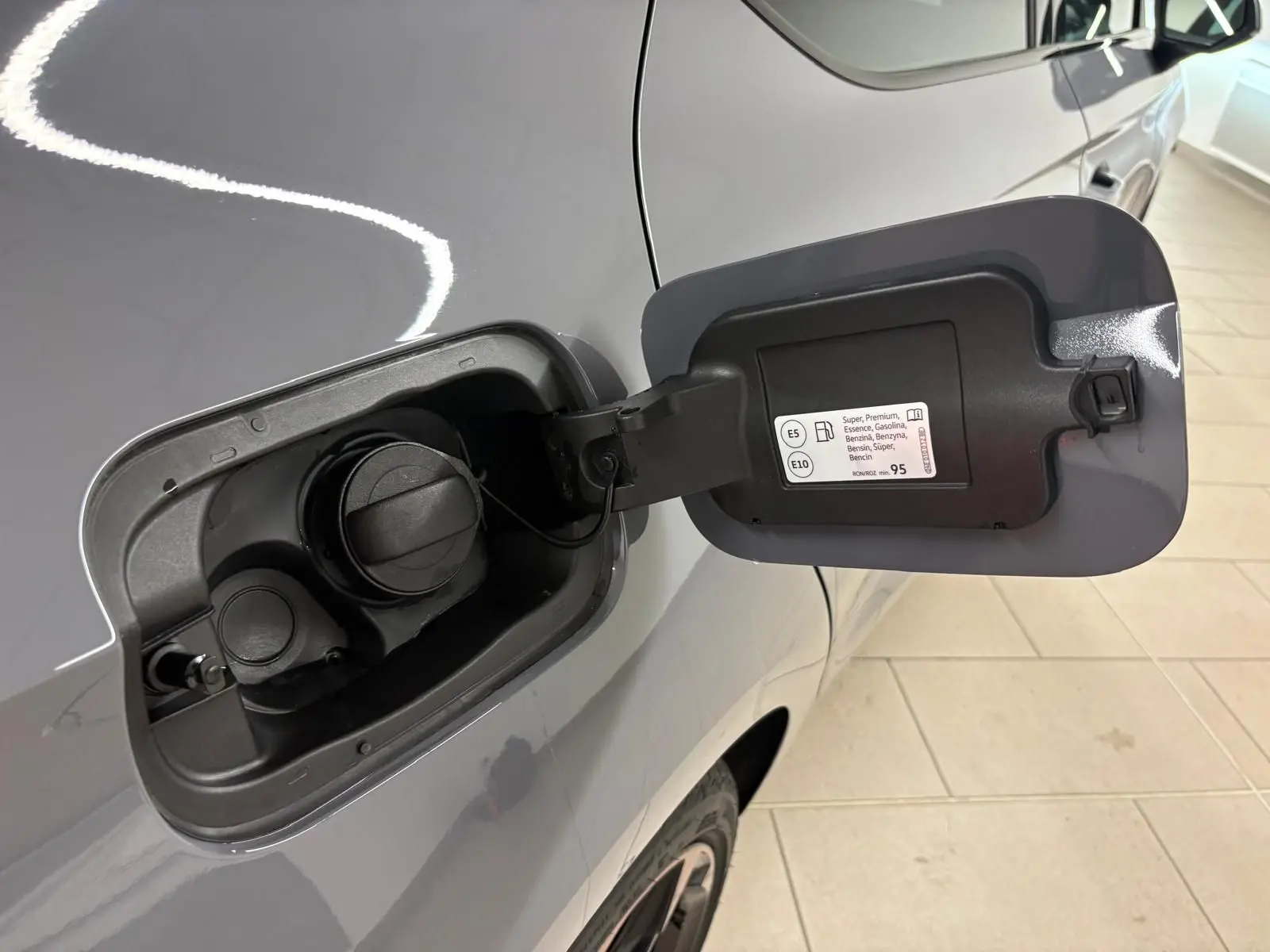 Gros plan sur la trappe à carburant côté gauche d'une CUPRA Leon gris Graphène avec jante alliage visible.