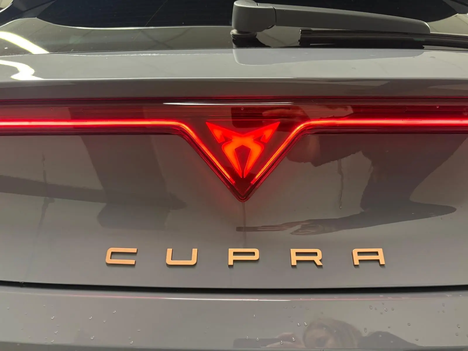 Gros plan sur le logo lumineux arrière rouge et l’inscription CUPRA sur la malle gris Graphène du Leon 2025.