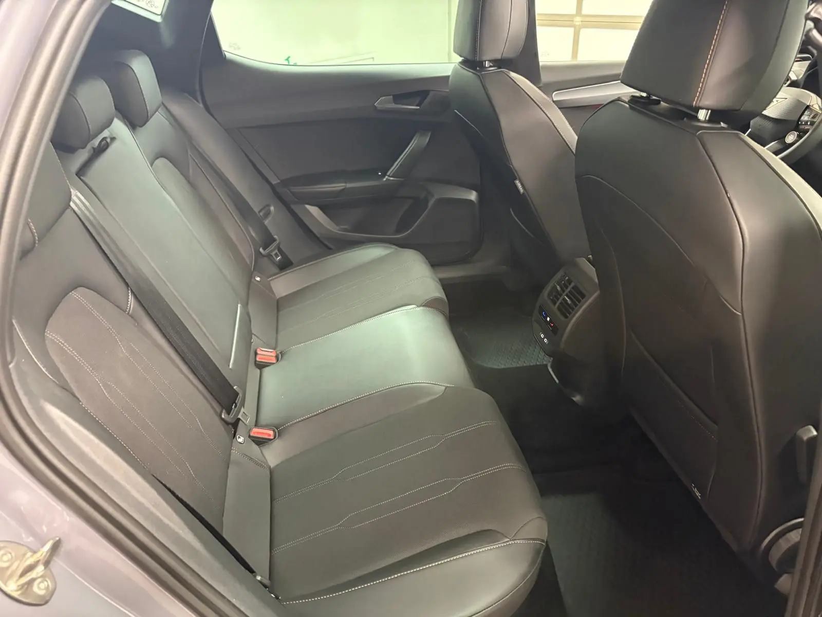 Vue intérieure arrière côté gauche de la CUPRA Leon Ph.2 gris Graphène, sièges en cuir noir avec surpiqûres contrastées.