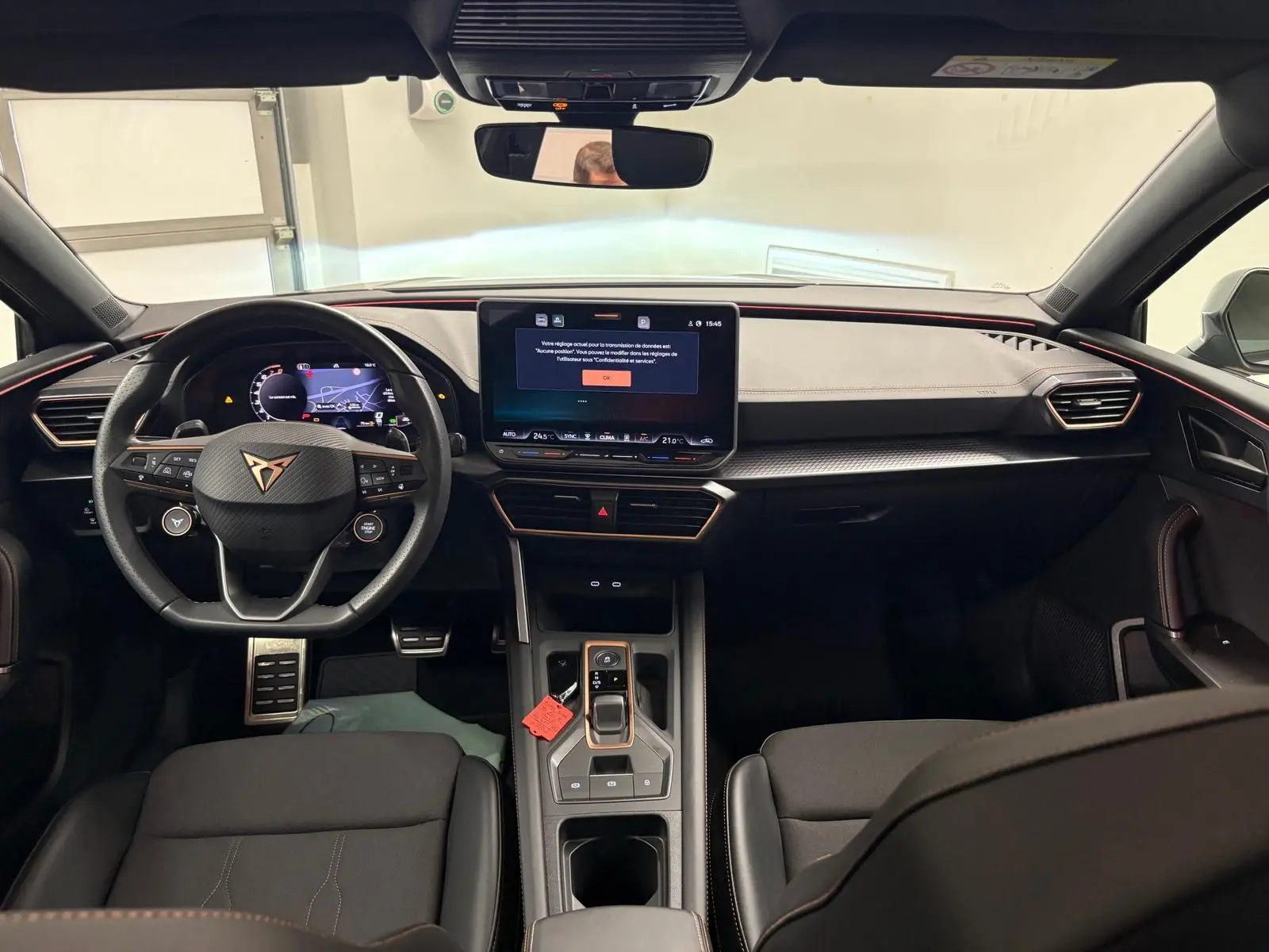 Vue intérieure avant du CUPRA Leon 2025, tableau de bord noir avec écran central tactile et volant multifonction au logo CUPRA.