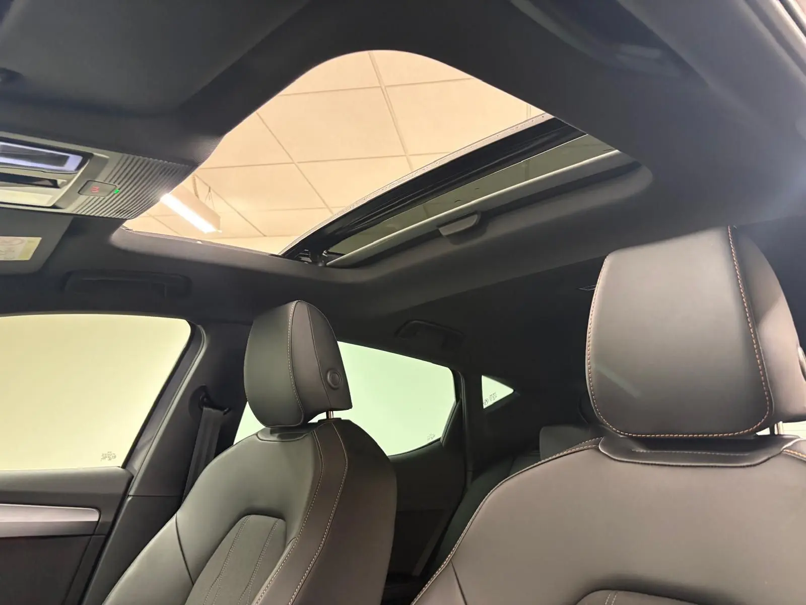 Vue intérieure du toit ouvrant panoramique et des sièges avant en cuir noir avec surpiqûres cuivrées d'une CUPRA Leon 2025.