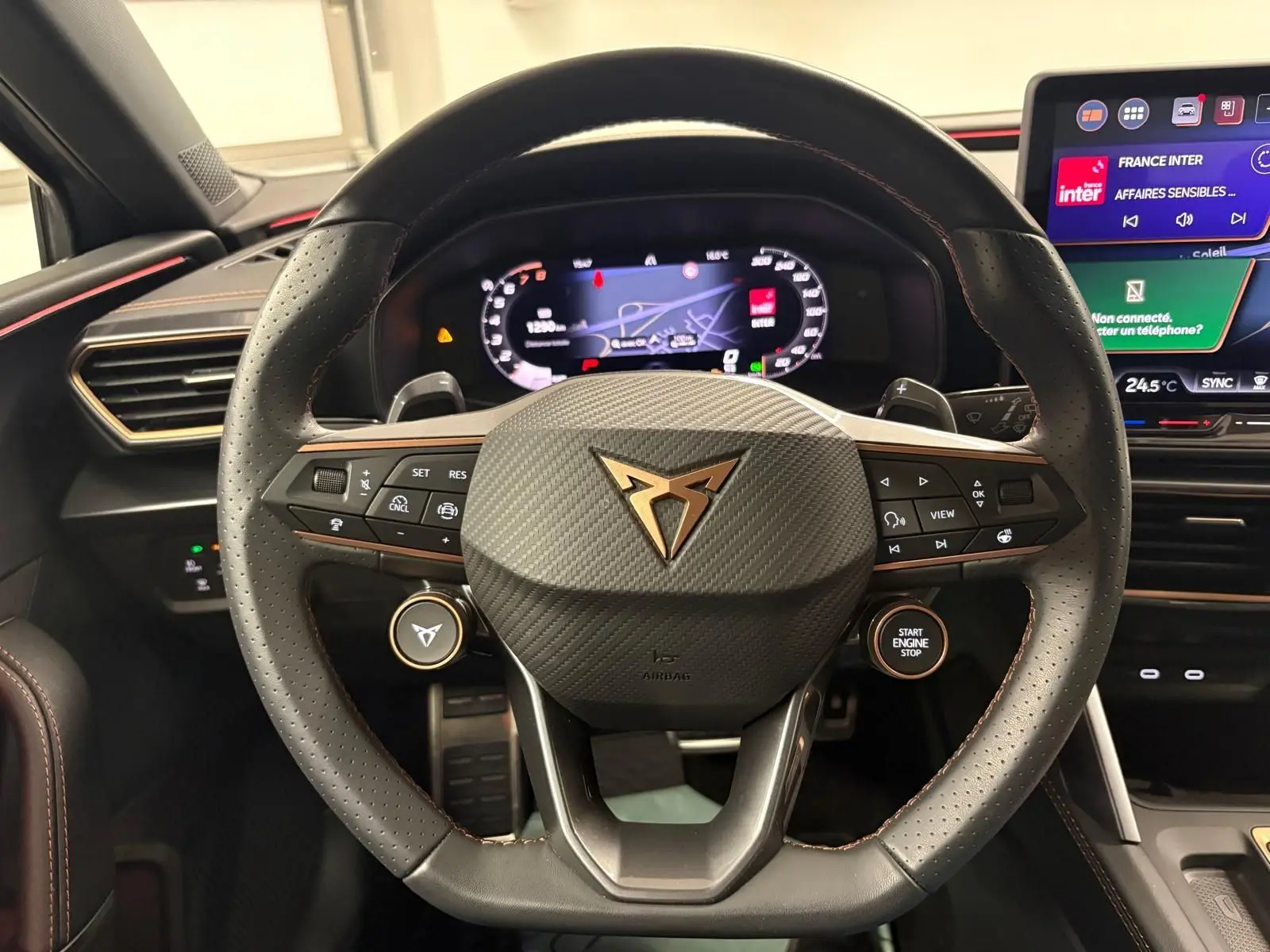 Vue rapprochée du volant cuir noir avec logo CUPRA cuivré et tableau de bord numérique de la CUPRA Leon 2025.