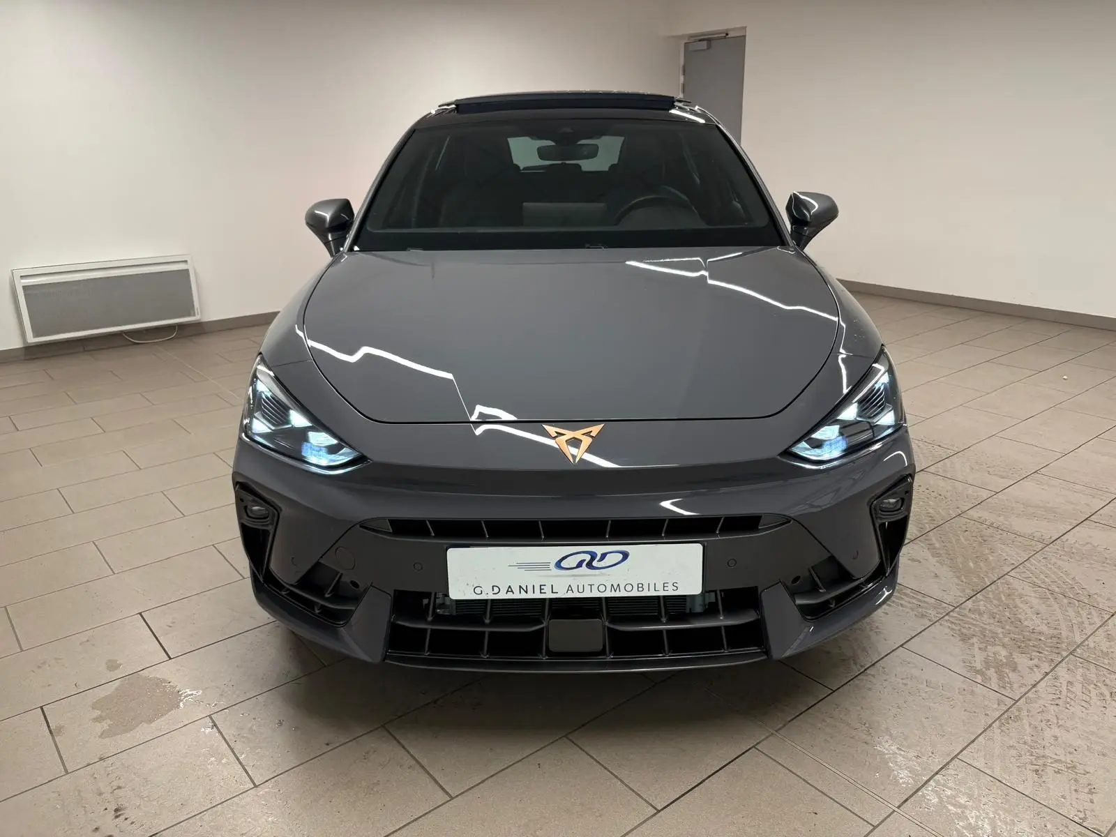 Vue avant d'une CUPRA Leon 2025 gris Graphène avec toit ouvrant panoramique et jantes cuivrées en alliage 18 pouces.