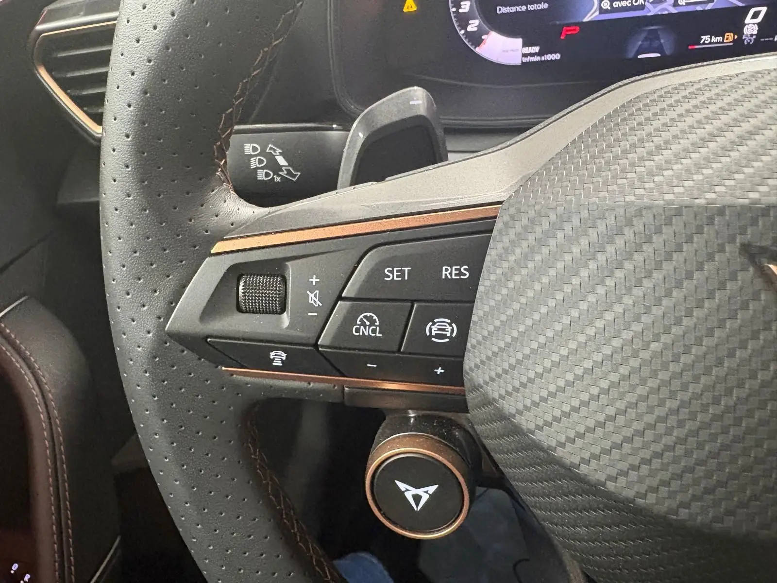Gros plan sur le volant en cuir perforé gris avec surpiqûres cuivrées et commandes multifonctions du CUPRA Leon 2025.
