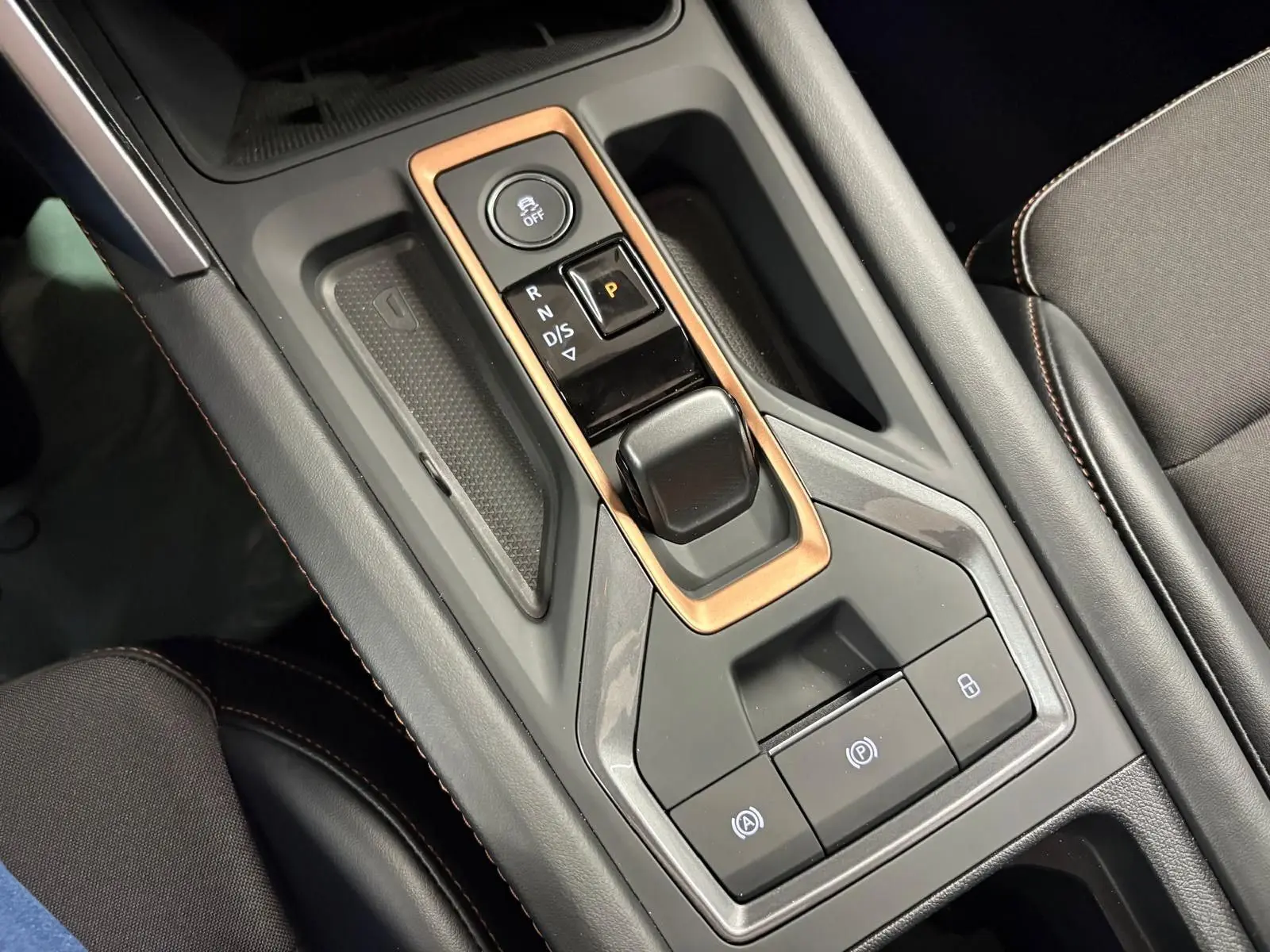 Gros plan sur la console centrale du CUPRA Leon 2025, avec levier de vitesses automatique et cadre cuivré.