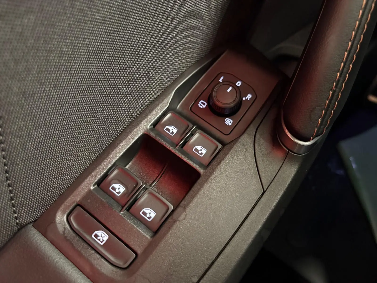 Gros plan sur la commande des vitres électriques et rétroviseurs côté conducteur du CUPRA Leon 2025, finition cuir noir.
