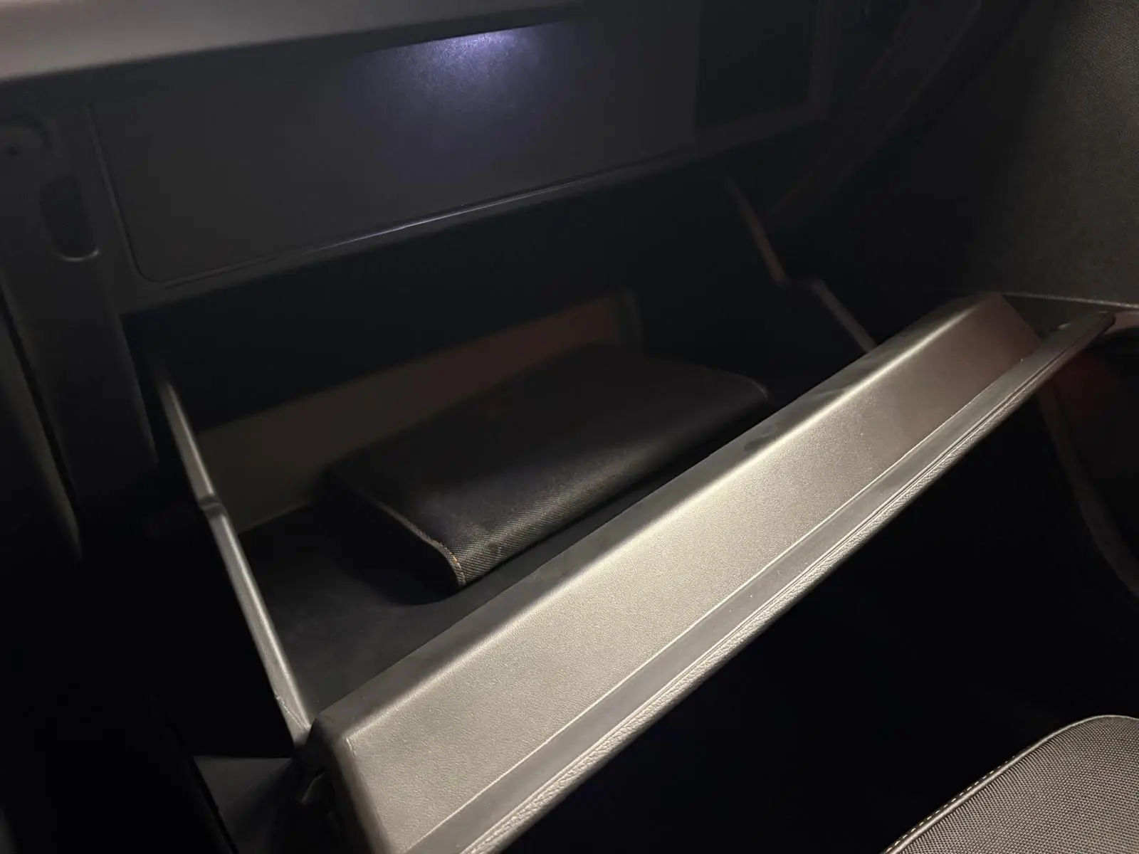 Gant de boîte à gants ouvert dans l'habitacle sombre d'une CUPRA Leon 2025, détail intérieur sobre.