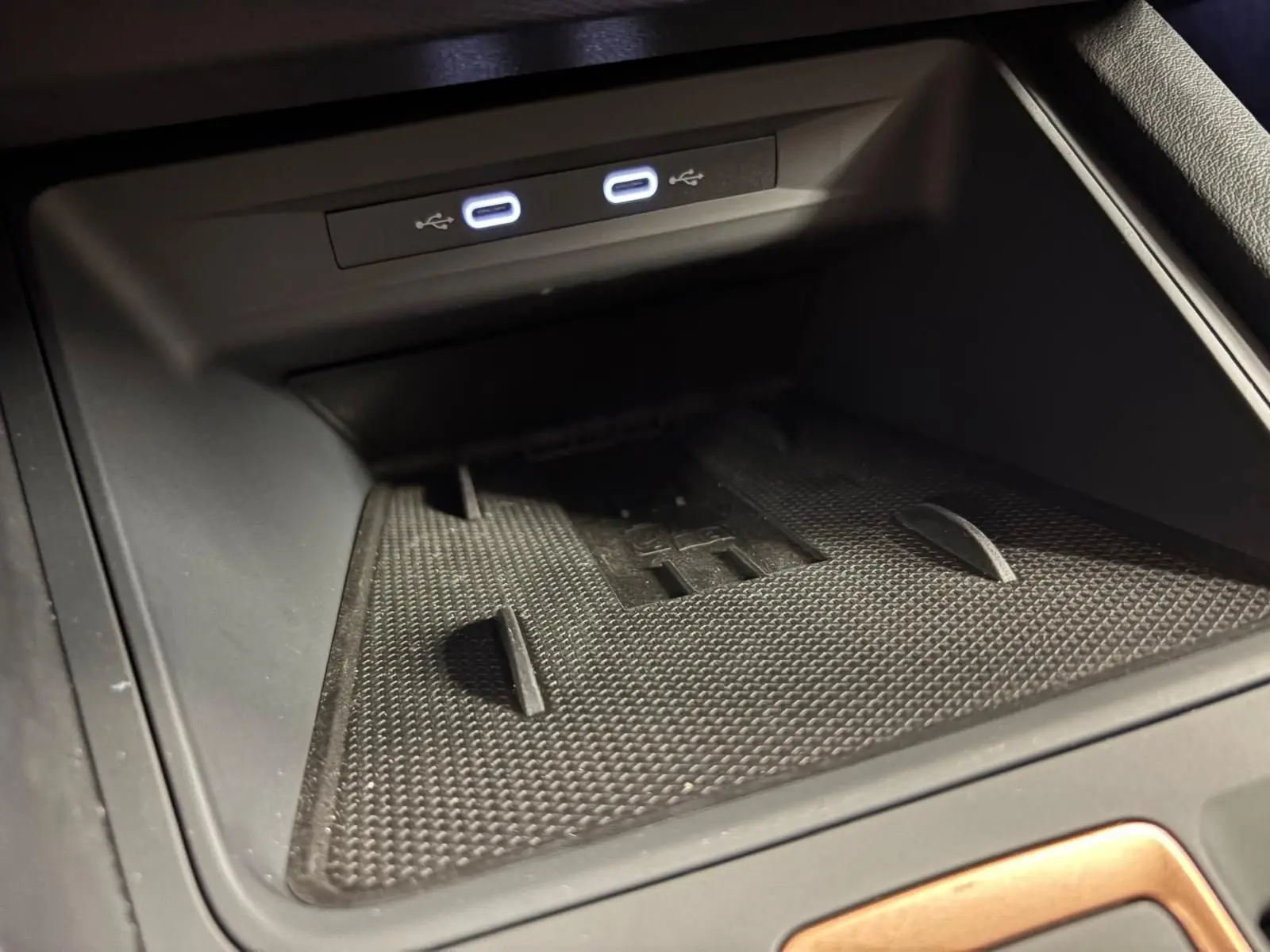 Gros plan sur la zone de recharge sans fil et ports USB lumineux dans l'habitacle noir du CUPRA Leon 2025.