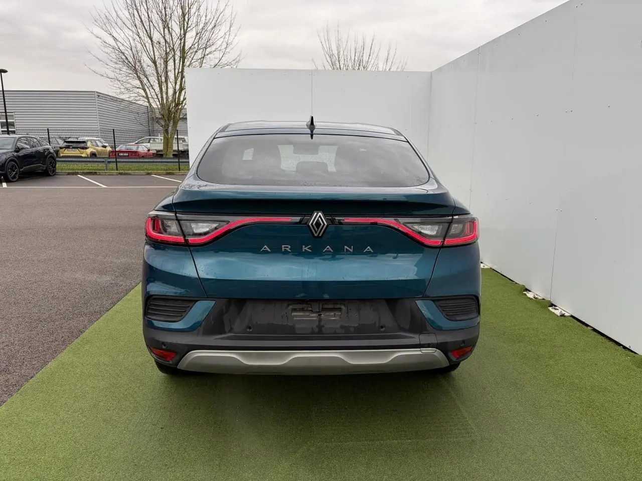 Vue arrière du Renault Arkana bleu Zanzibar métal avec feux LED reliés par un bandeau lumineux rouge.