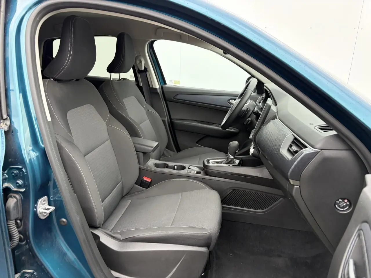 Vue intérieure côté conducteur de la Renault Arkana bleu Zanzibar, montrant les sièges avant et la console centrale.