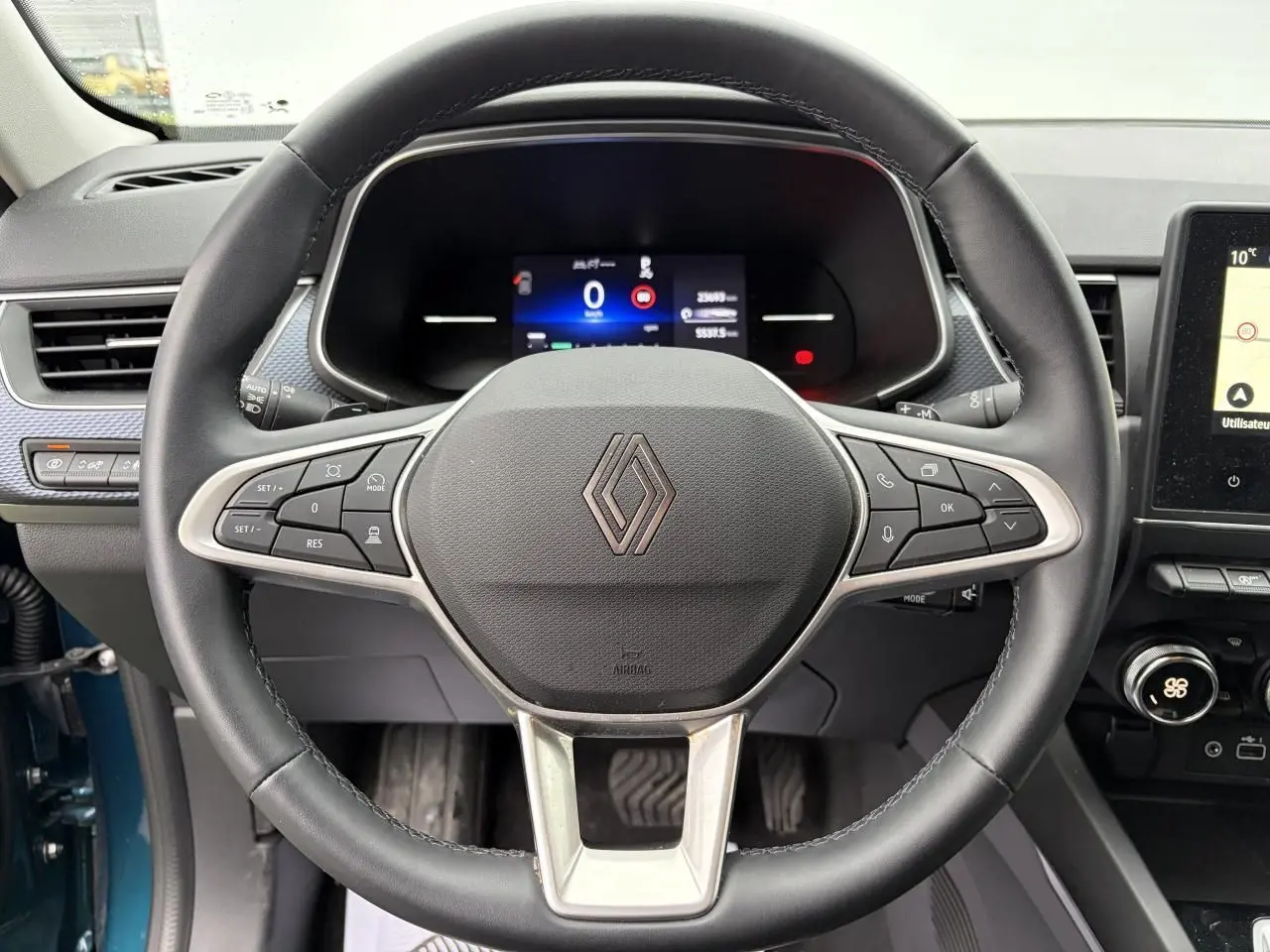 Vue intérieure centrée sur le volant noir de la Renault Arkana 2025 avec tableau de bord numérique et détails argentés.