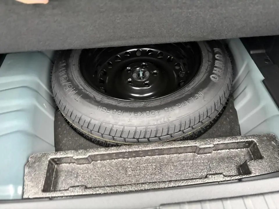 Gros plan sur la roue de secours noire dans le coffre d'une Renault Arkana 2025, détail du rangement sous plancher.