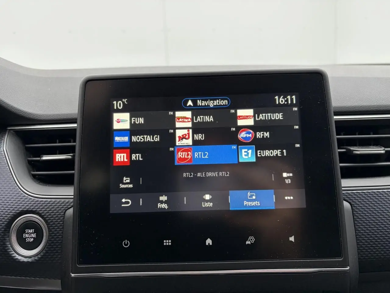 Écran tactile central de la Renault Arkana 2025 affichant les stations radio, entouré de la console noire texturée.