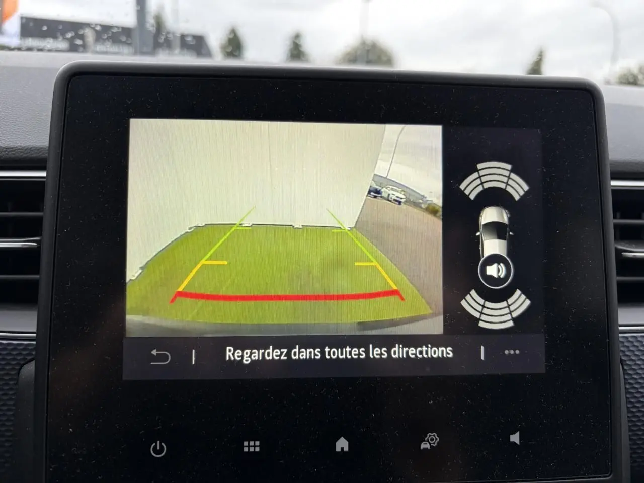 Écran de caméra de recul du Renault Arkana 2025 affichant les lignes de guidage et l'alerte sonore de proximité.