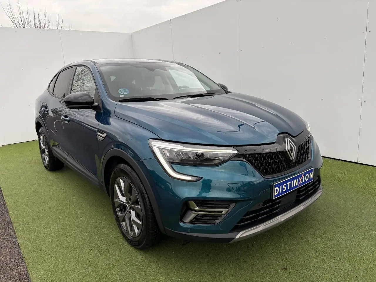 Renault Arkana bleu Zanzibar métal en 3/4 avant droit, avec calandre noire et jantes alliage grises 17 pouces.