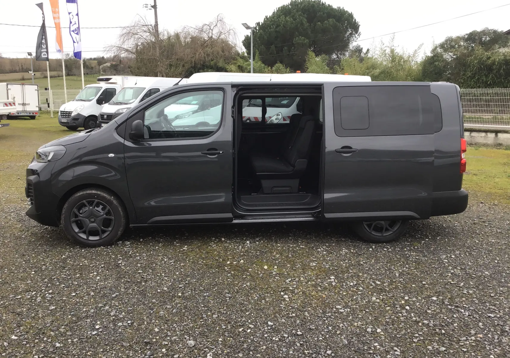 Vue latérale gauche du FIAT Scudo Combi gris titane avec porte coulissante ouverte dévoilant les sièges arrière.