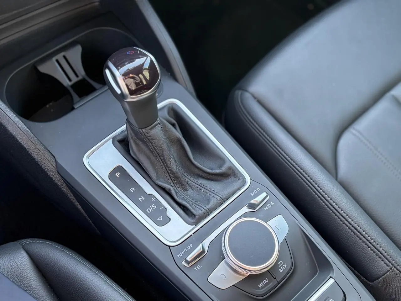 Gros plan sur la console centrale avec levier de vitesses automatique et commandes MMI en cuir noir.