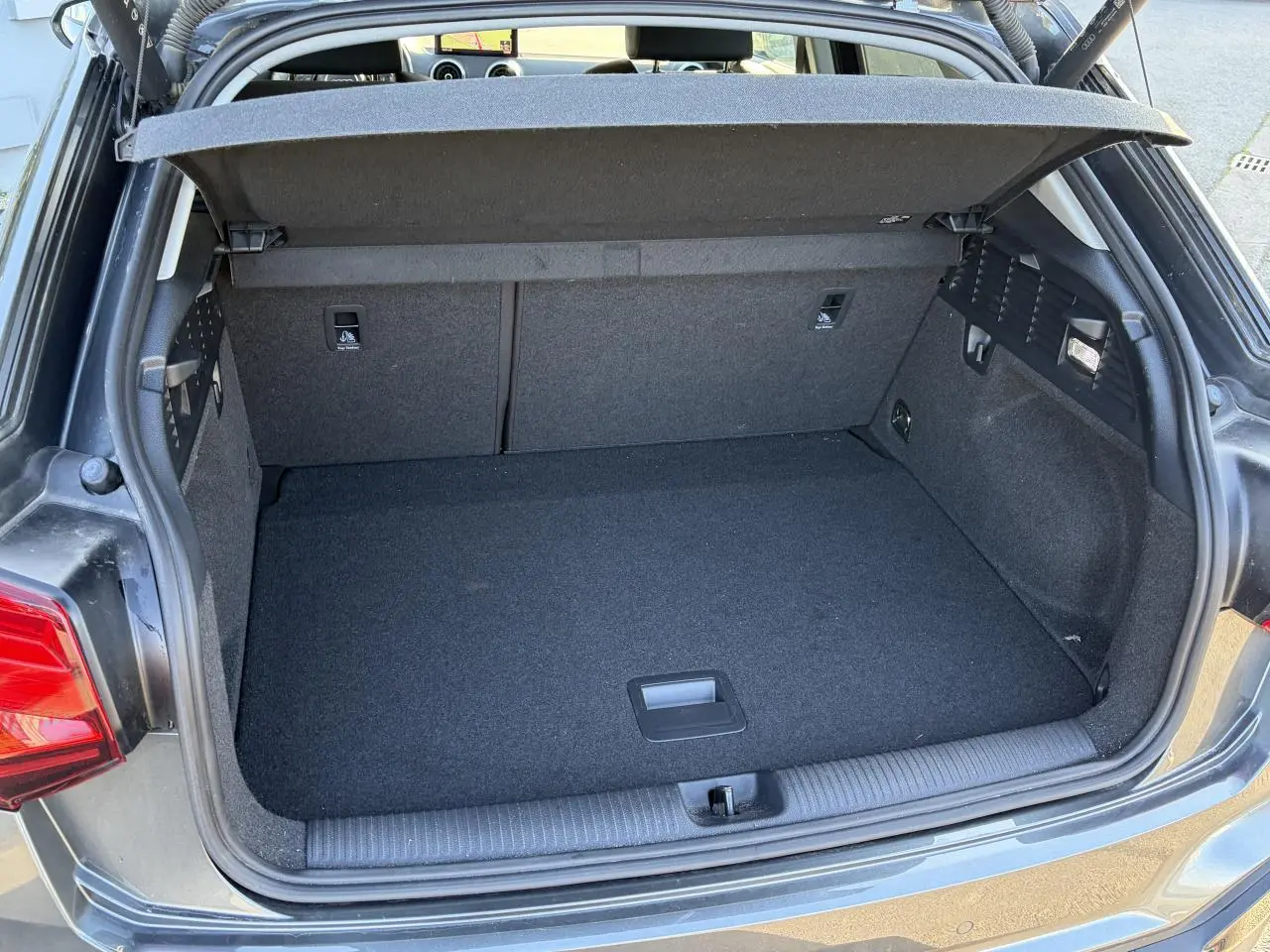 Vue arrière du coffre ouvert de l'Audi Q2 gris Daytona, montrant l'espace de chargement et le hayon électrique.