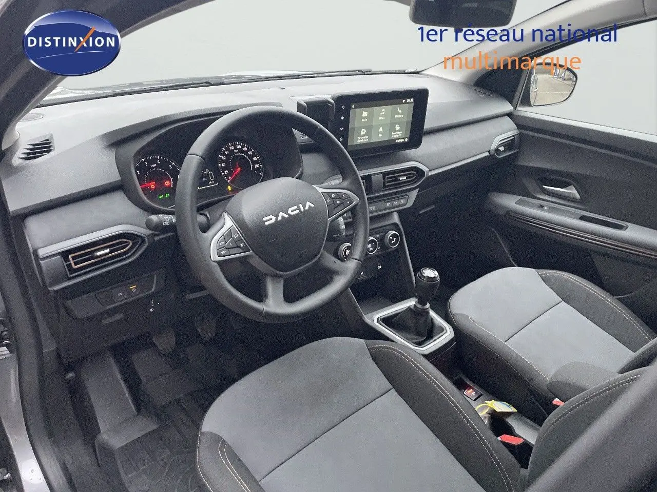 Vue intérieure côté conducteur du Dacia Jogger gris schiste, montrant le tableau de bord, volant multifonction et console centrale avec boîte manuelle.