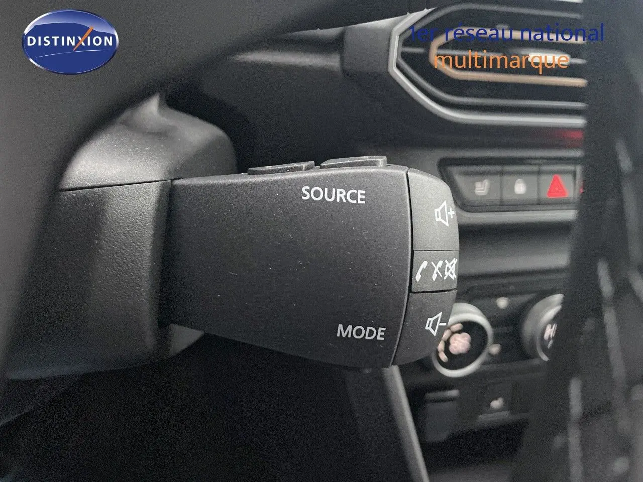 Gros plan sur la commande au volant du DACIA JOGGER gris schiste métal, avec boutons source et mode visibles.