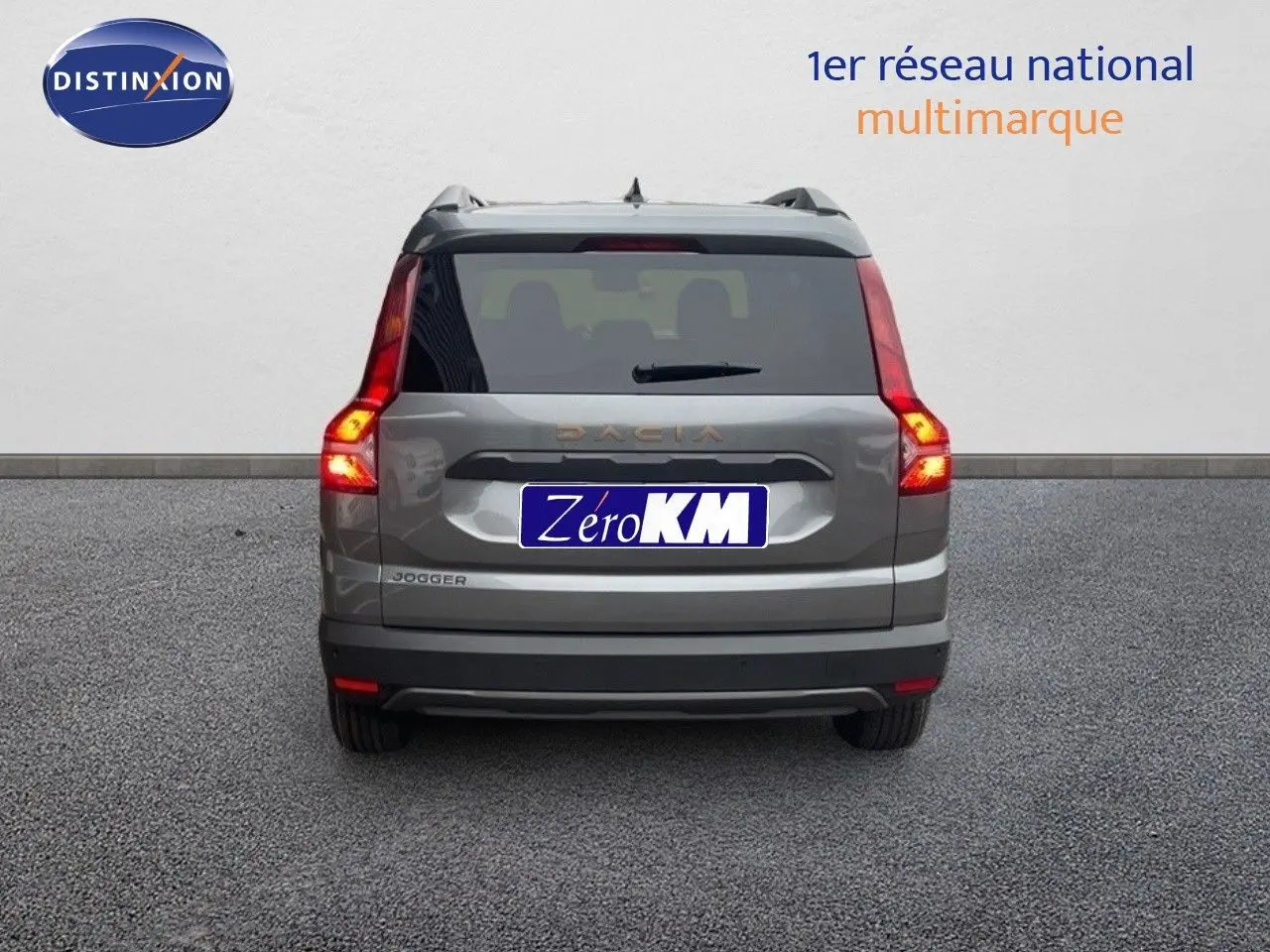 Vue arrière d'un Dacia Jogger gris schiste métal avec feux allumés, sur fond neutre en extérieur.
