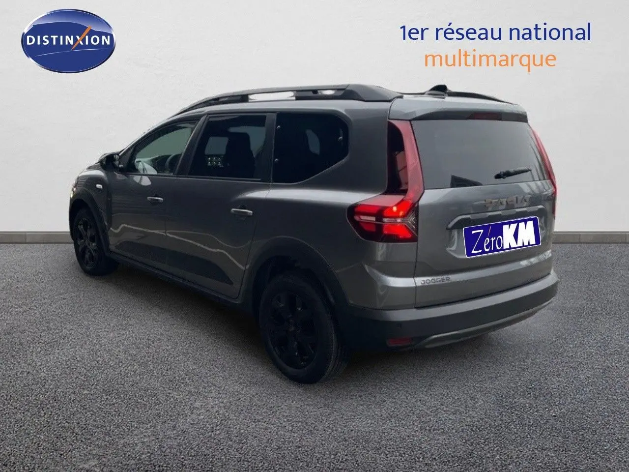 Vue 3/4 arrière droite d'un Dacia Jogger gris schiste métal avec feux arrière allumés et jantes noires.