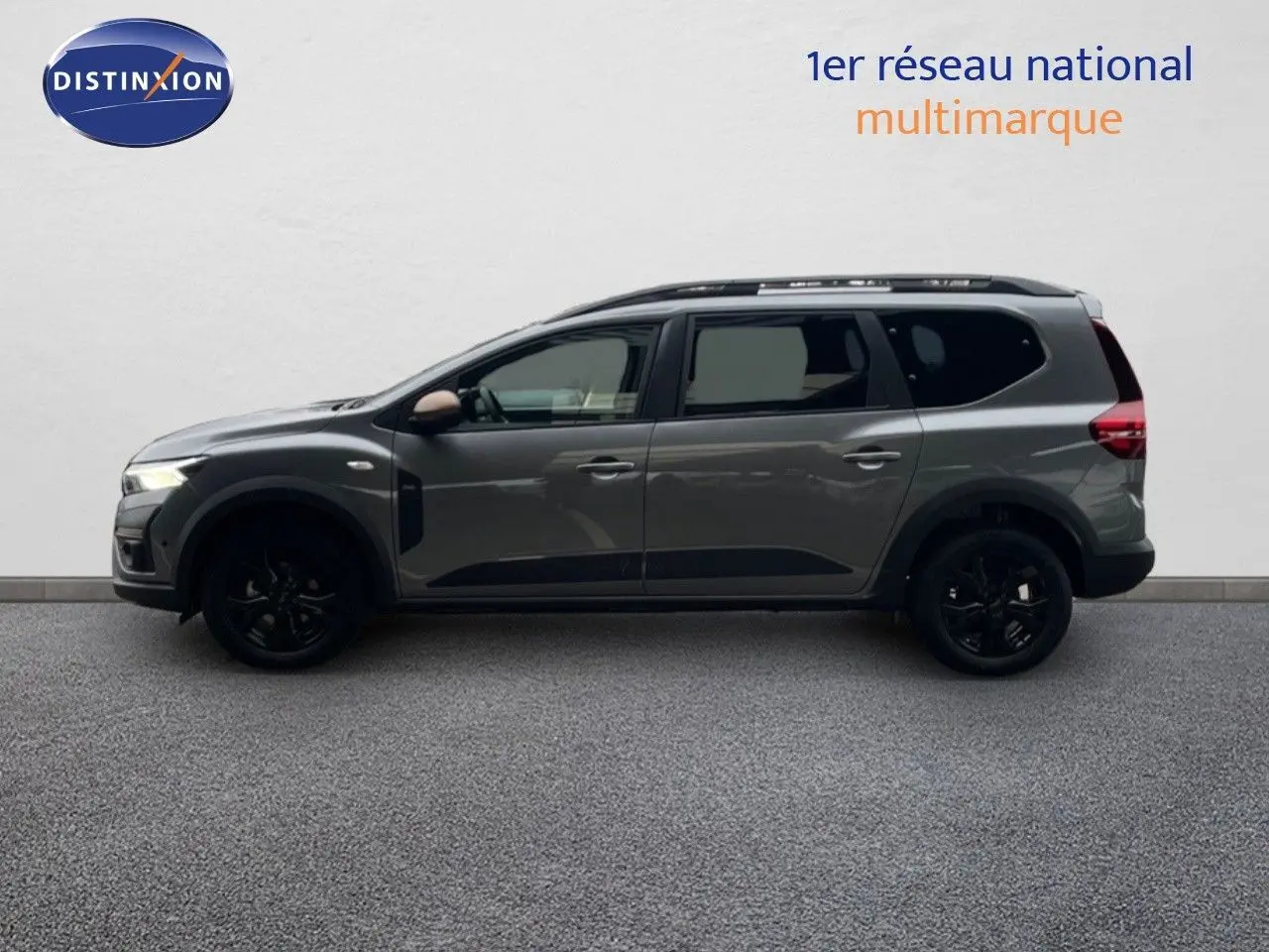 Vue de profil côté gauche du Dacia Jogger gris schiste métallisé avec jantes noires et barres de toit.