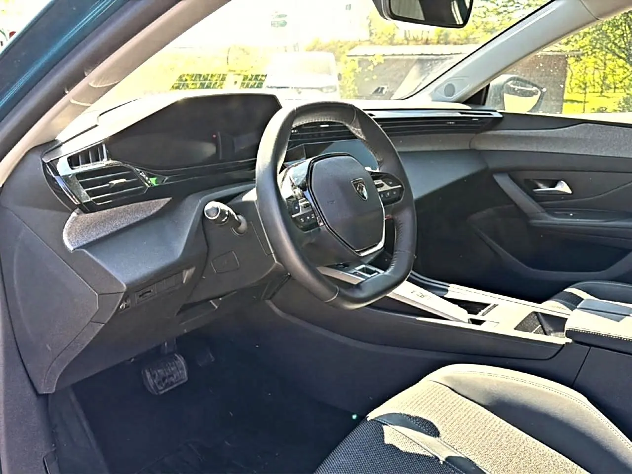 Vue intérieure côté conducteur du Peugeot 408 Hybrid 145 allure 2025, volant cuir et tableau de bord moderne noir.