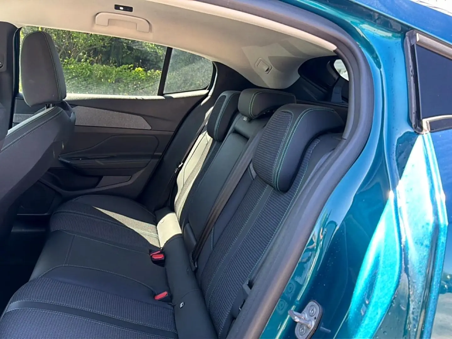 Vue intérieure arrière côté droit d'une Peugeot 408 bleu 2025, montrant la banquette 3 places en tissu et cuir avec appuie-têtes.