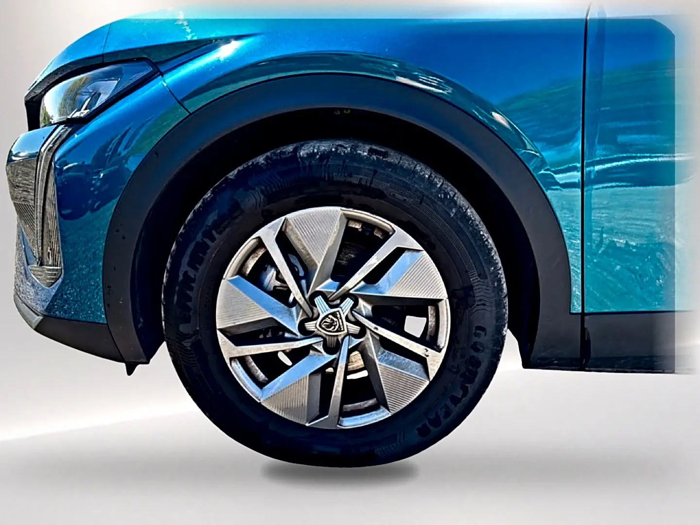 Gros plan sur la roue avant gauche d’une Peugeot 408 Hybrid 145 allure e-dcs6 bleu avec jante alu au design moderne.