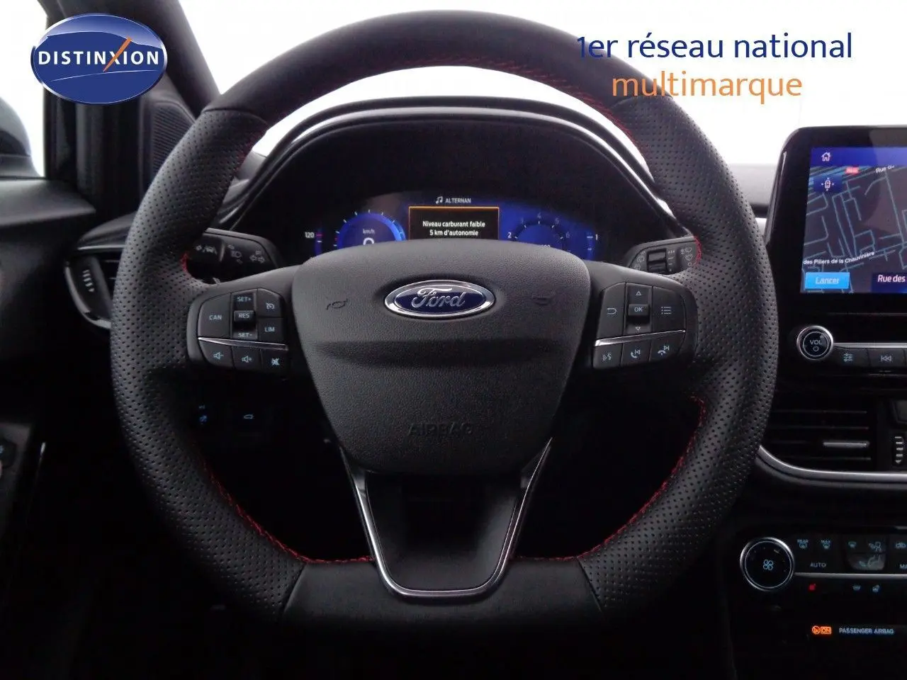 Vue rapprochée du volant perforé avec surpiqûres rouges et tableau de bord numérique de la Ford Puma gris Solar Metal 2022.