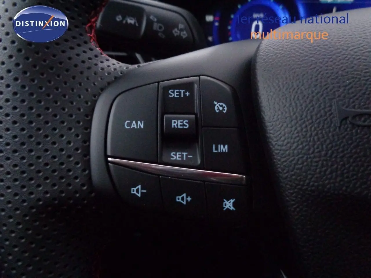 Gros plan sur les commandes du volant en cuir perforé noir du Ford Puma 2022, boutons de régulateur de vitesse et volume sonore.