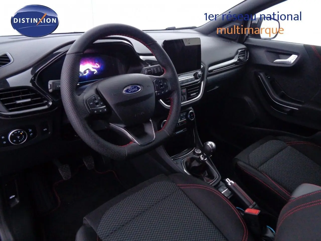 Intérieur avant droit du Ford Puma 2022, volant cuir noir avec surpiqûres rouges et console centrale avec boîte manuelle.