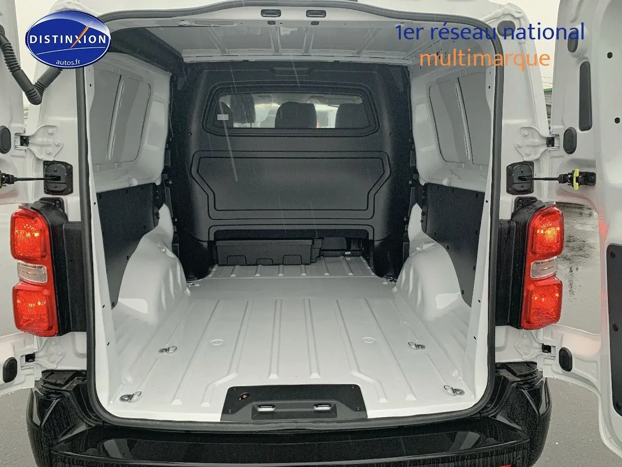 Vue arrière du fourgon blanc Peugeot Expert Long 2023, portes ouvertes dévoilant l'espace de chargement vide et spacieux.