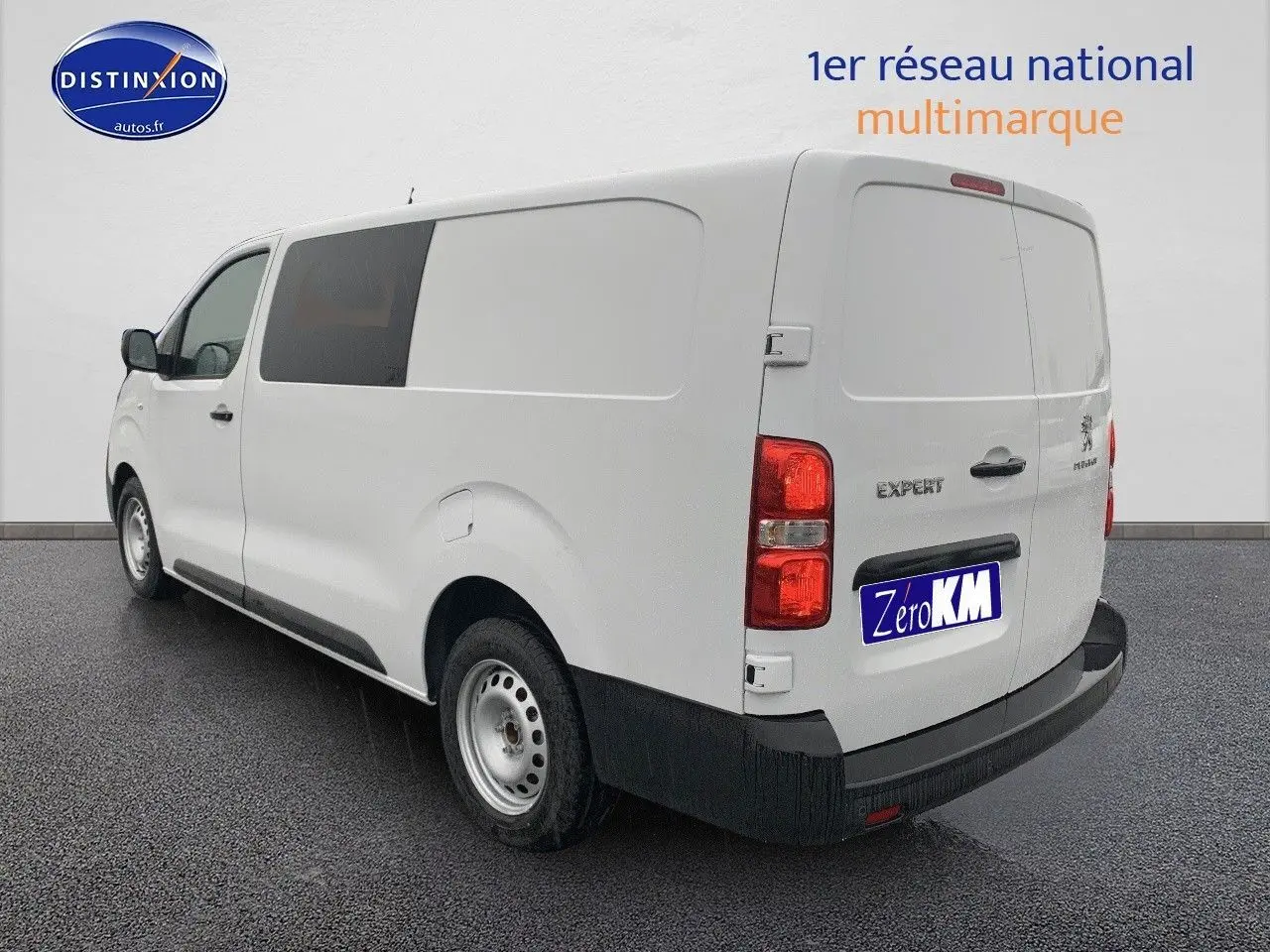 Vue 3/4 arrière droite d'un Peugeot Expert blanc 2023 version Long avec portes arrière fermées sur sol noir.