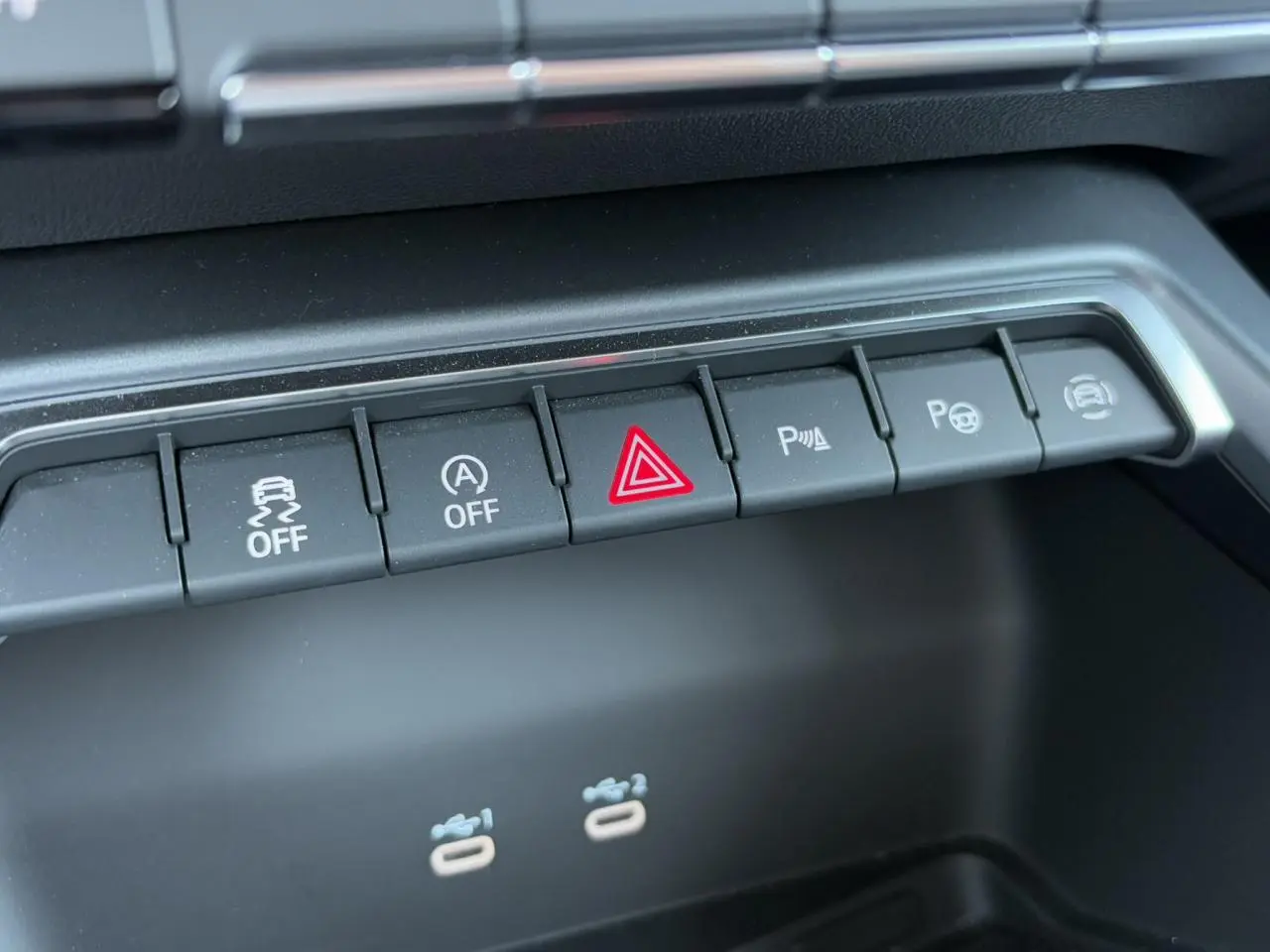 Gros plan sur les boutons de commande du tableau de bord de l'Audi A3 Sportback 2024 blanc Arkona, avec alertes et assistances.