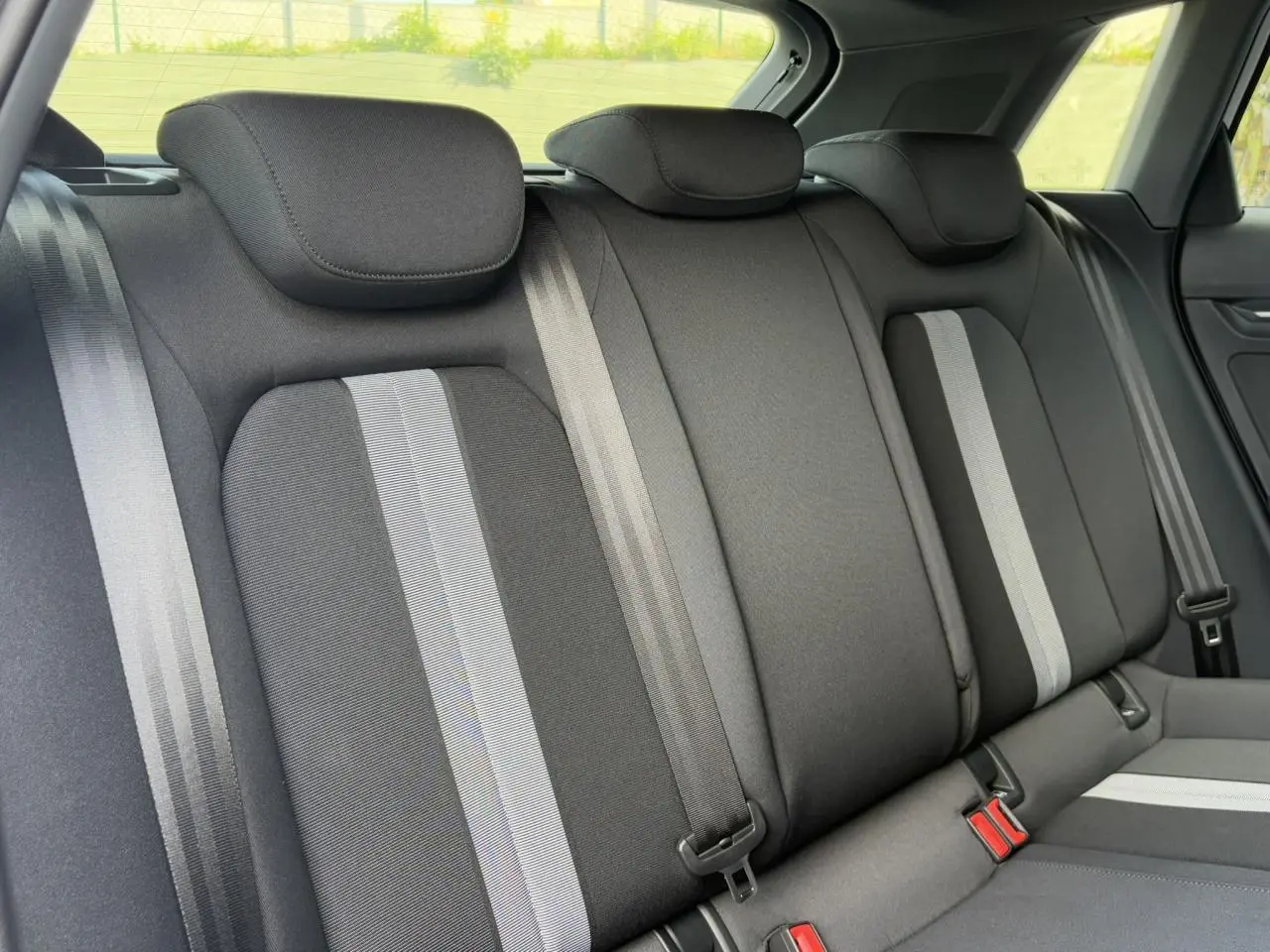 Vue intérieure arrière des sièges en tissu gris foncé avec bandes claires de l'Audi A3 Sportback 2024.