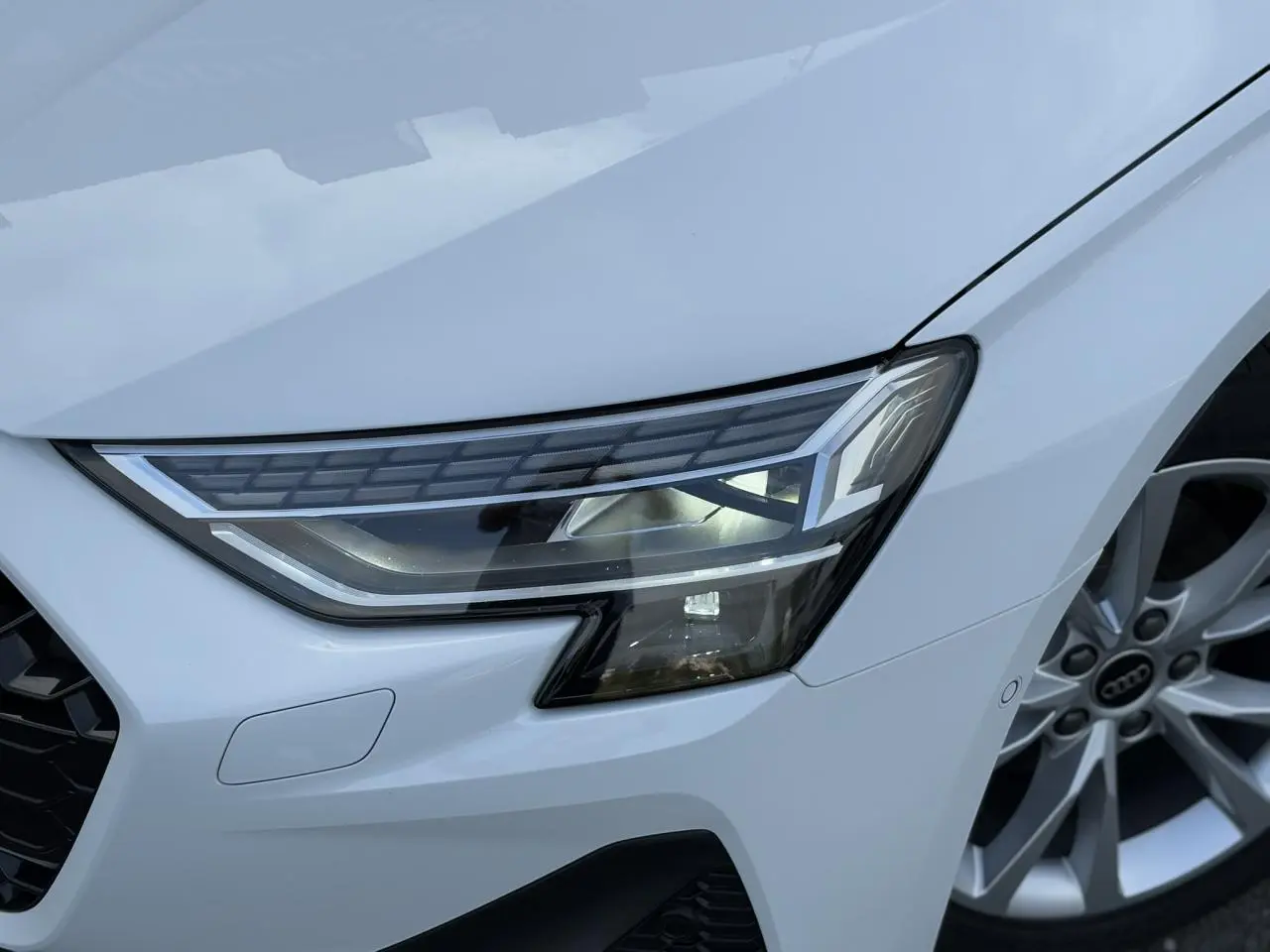 Gros plan sur le phare Matrix LED avant droit et la jante alliage 17 pouces d'une Audi A3 Sportback Blanc Arkona 2024.