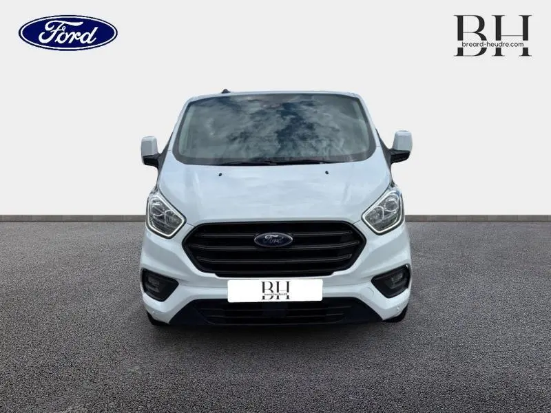 Vue de face du Ford Transit Custom Fourgon blanc glacier 2023 avec calandre noire et phares modernes.