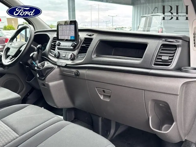 Intérieur du Ford Transit Custom blanc glacier, vue du tableau de bord et volant côté gauche avec écran tactile central.